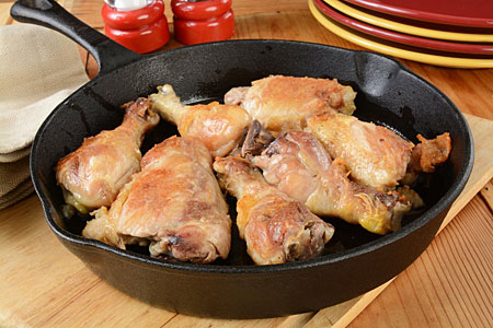 A bunch of pieces of chicken frying in a pan.